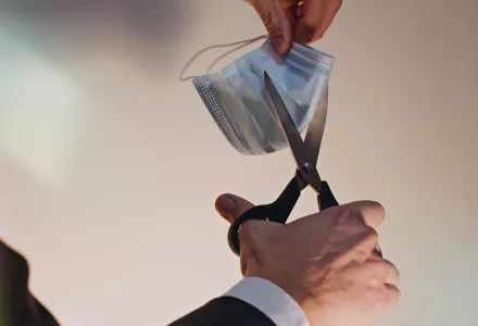 person cutting a surgical mask