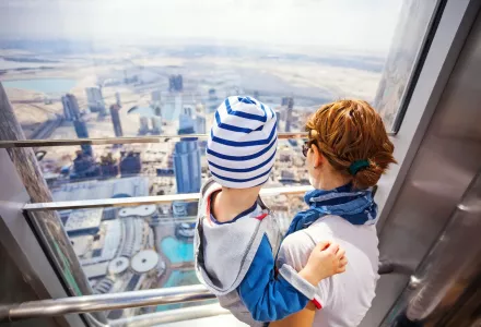 A mother holds her young child overlooking Dubai from the observation deck of the Burj Khalifa.
