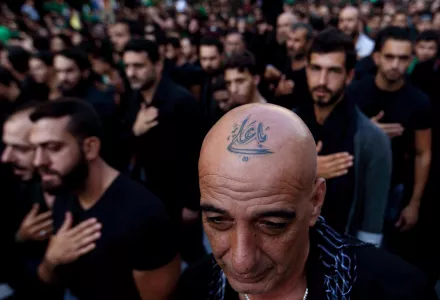 In this Saturday, Oct. 24, 2015 file photo, a Lebanese Shiite supporter of Hezbollah with a tattoo on his head that reads in Arabic, "Oh Ali", beats his chest during the holy day of Ashoura, in the southern suburb of Beirut, Lebanon.