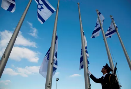A member of the Knesset guard lowers the Israeli flags to half-staff in preparations to display the coffin of former Israeli President Shimon Peres at the Knesset, Israel's Parliament, in Jerusalem, Wednesday, Sept. 28, 2016.