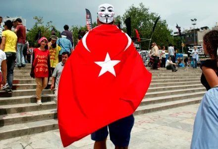 Giulio Giacomazzi 34, a tourist from Brazil wearing a Turkish flag and a mask enters Gezi Park, near Taksim square in Istanbul, Friday, June 7, 2013.