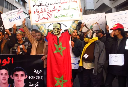 An activist wearing a skull mask and the flag of Morocco with a sign, saying the 'February 20th pro-democracy movement does not fear cowards and the corrupt' and is supported by the citizens, leads a demonstration in the capital Rabat Sunday, Feb. 19, 2019