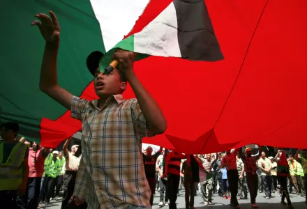 Jordanian youths chanting slogans carry a large Jordanian flag at an anti-government demonstration in Amman, Jordan Friday, July 29, 2011.