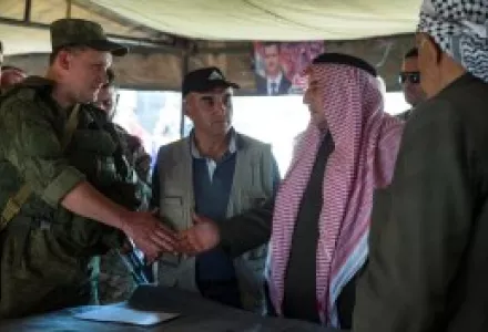Sheikh Ahmad Mubarak, second from right, shakes hands with a Russian military officer after signing a cease-fire declaration in Maarzaf, about 15 kilometers west of Hama, Syria.