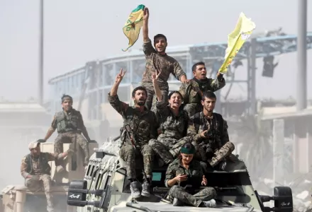 Syrian Democratic Forces (SDF) fighters ride atop of military vehicles as they celebrate victory in Raqqa, Syria.