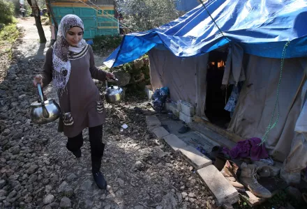 A Syrian refugee woman, holds teapots as she walks past her tent during the visit of the United Nations High Commissioner for Refugees, UNHCR, chief Antonio Guterres, not seen. at a small refugee camp, in Ketermaya village southeast of Beirut, Lebanon, Thursday March 14, 2013.