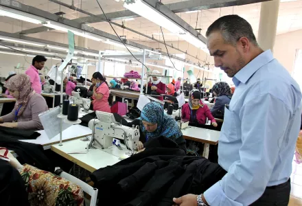 In this Wednesday, May 20, 2015 photo, manager Maher Howeidi inspects production at a garment factory in the village of Kitteh in northern Jordan where dozens of Jordanian women sew jeans for the U.S. market.