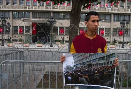 Mohamed Al Hui, 18, standing in front the Interior Ministry, holds a poster of the Ministry during the Revolution on Jan.14, 2011, on Tunis main avenue to mark the second anniversary of the Revolution, Monday, Jan.14, 2013.