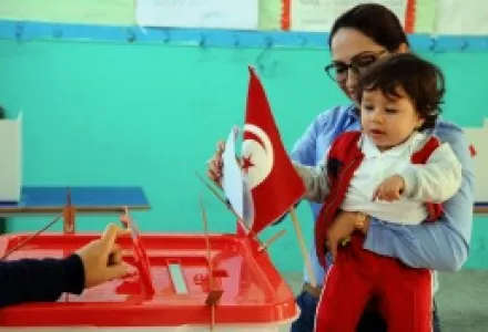 A woman casts her vote with her child, during the first round of the Tunisian presidential election, in a polling station at Marsa, outside Tunis.