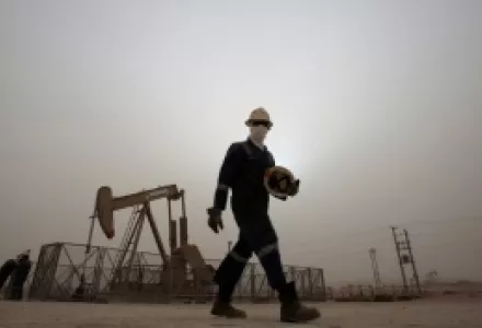 An oil worker walks by an oil pump during a sandstorm that blew in, in the desert oil fields of Sakhir, Bahrain.