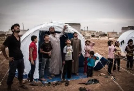 Displaced Syrians watching a Russian war plane above a camp on the southern outskirts of the northern Syrian city of Aleppo on October 22, 2015.
