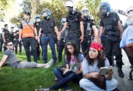 People sit on the grass as riot police ask them to leave Gezi Park in Istanbul, Turkey, Monday, July 8, 2013.