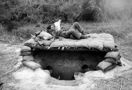 GIs take time out to read newspapers and magazines above and below their sandbagged bunker in a base camp set up in a jungle clearing in South Vietnam near the Cambodian border, Nov. 28, 1966. 