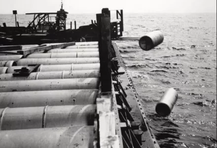 A forklift shovels one-ton containers of mustard gas over the side of a barge somewhere in the Atlantic Ocean in 1964. The Army dumped millions of pounds of chemical warfare agent over decades in this way.   