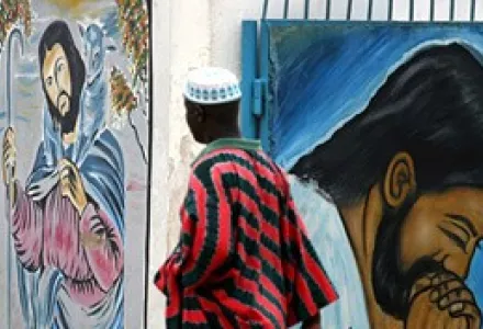 A Muslim man walks past a church gate decorated with paintings of Jesus Christ in Lagos, Nigeria,  April 10, 2005.