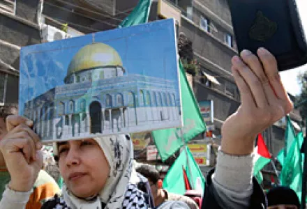 A Palestinian woman holds the Quran and a picture of the gold-capped Dome of the Rock during a march held at the Palestinian refugee camp of Yarmouk, near Damascus, Syria, Mar. 17, 2010.