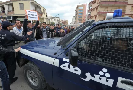 A protestor holds a placard reading "For a transition period" as he confronts a police vehicle, during a demonstration, in Bejaia, eastern Algeria, Saturday, April 5, 2014. Demonstrators call for a boycott of the upcoming presidential election as twelve candidates have registered for Algeria’s April 17 presidential election including President Abdelaziz Bouteflika, 77, who is running for a fourth term.