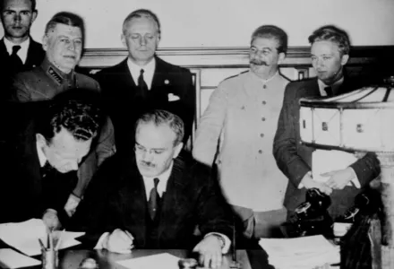 Vyacheslav Molotov, Soviet foreign minister, signs the non-aggression pact negotiated between the Soviet Union and Germany at the Kremlin, Moscow. Standing behind him is his German counterpart Joachim von Ribbentrop (left), and Joseph Stalin (2nd from right), 23 August 1939.