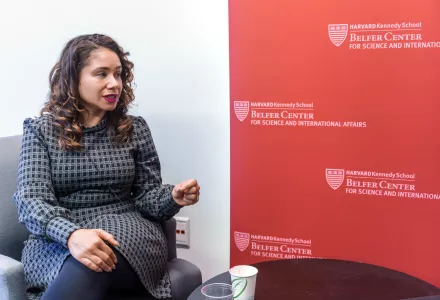 Desirée Cormier Smith seated and speaking at left and a crimson banner with the Belfer Center world mark at right. 