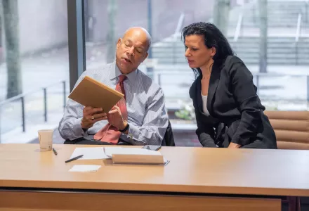 Photo of Juliette Kayyem and Jeh Johnson looking at a publication during a seminar.