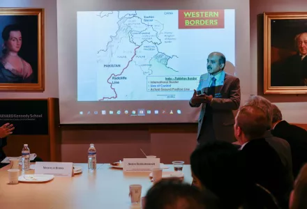 Arjun Subramaniam speaks in front of a slide presentation