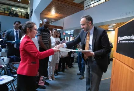 Professor Tarek Masoud congratulates new U.S. citizens as he hands them their naturalization certificates.