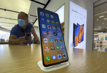 Photo of a visitor to a Huawei retail store stands near a Huawei smartphone displaying a variety of apps in Beijing on Tuesday, Sept. 8, 2020.