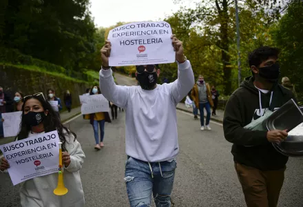 People hold up banners in support of the hotel industry that read: "I search for work", in Pamplona, northern Spain, Wednesday, Oct. 21, 2020, while protesting with others against the new measures against the coronavirus in the Navarra province where all bar and restaurants will be closed for 15 days from midnight Wednesday.