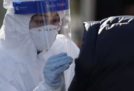 A medical worker wearing protective gear takes samples from a woman during a COVID-19 testing at a coronavirus testing site in Seoul, South Korea on Dec. 12, 2020.