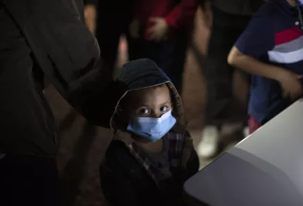 An unaccompanied minor looks up as he waits to answer questions from a U.S. Border Patrol agent at an intake site after he was smuggled on an inflatable raft across the Rio Grande river in Roma, Texas, Wednesday, March 24, 2021. 