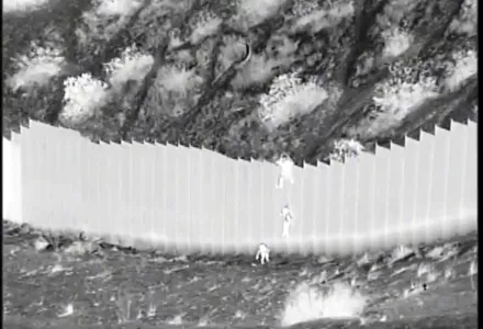 This photo taken from night video provided by the U.S. Customs and Border Protection shows a smuggler dropping children from the top of border barrier in Santa Teresa, N.M.
