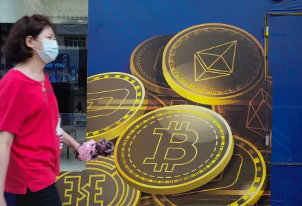 In this June 1, 2021, file photo, a woman walks past an advertisement for the Bitcoin cryptocurrency in Hong Kong.