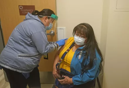 pharmacist administers COVID-19 vaccine to patient