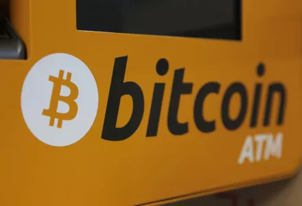 A photo of a sign that reads "bitcoin ATM" on a yellow background.