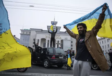 A man celebrates holding a Ukrainian flag over his head.