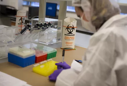 Image of a scientist in protective gear conducting biological research using micro pipettes and capillary tubes.