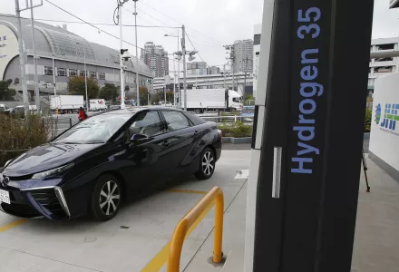 A car parked next to a hydrogen fuel pump in Japan with the text "hydrogen 35" vertically on the side.
