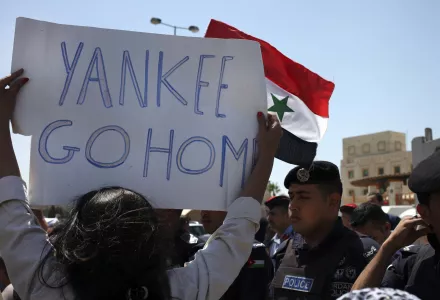 Jordanian security police stand in front of protesters waving the Syrian national flag and holding an anti-American poster during a protest against any American military strike on Syria, near the U.S. embassy, Amman, Jordan, Saturday, Aug. 31, 2013. The United States is considering launching a punitive strike against the regime of Syrian President Bashar Assad, blamed by the U.S. and the Syrian opposition for an Aug. 21 alleged chemical weapons attack in a rebel-held suburb of the Syrian capital of Damascus