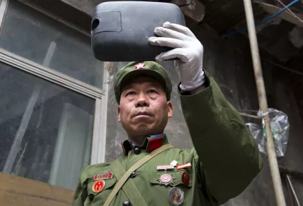 In this May 2, 2016 photo, People’s Liberation Army veteran Zhao Shunli uses a rear view mirror to refine his look at his home in Luoyang in central China’s Henan province.