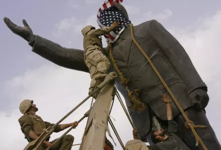 Cpl. Edward Chin of the 3rd Battalion, 4th Marines Regiment, covers the face of a statue of Saddam Hussein with an American flag before toppling it in downtown in Baghdad on Wednesday, April 9, 2003. (AP Photo/Jerome Delay, File)