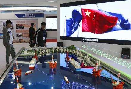 Visitors look at the models of oil tanker shaped floating nuclear reactors and oil rigs showcased at the display booth of China's state-owned China National Nuclear Corporation during the China International Exhibition on Nuclear Power Industry in Beijing. April 27, 2017 (Andy Wong/Associated Press).