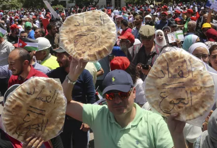 Jordanian protesters shout "bread" in front of the Labour Union offices in Amman, Jordan Wednesday, June 6, 2018. "Corruption equals hunger," is written in Arabic on loaves of bread. (AP Photo/Raad al-Adayleh)