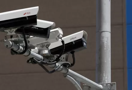 People walk by Chinese-made surveillance cameras.