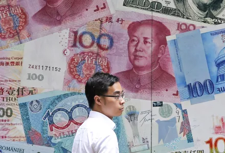 In this June 10, 2019, file photo, a man walks past a money exchange shop decorated with different banknotes at Central, a business district of Hong Kong.