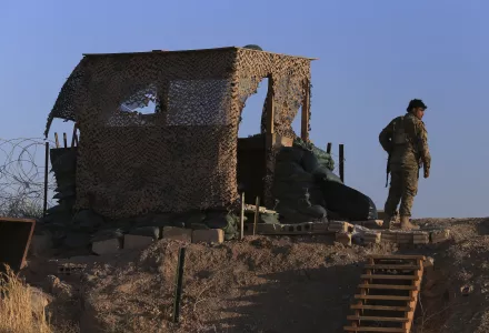 A fighter from the Syrian Democratic Forces, SDF, stands inside a post where U.S. troops were based, in Tel Abyad town, at the Syrian-Turkish border, Syria, Monday, Oct. 7, 2019. 