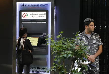 A woman uses ATM outside a bank, as a Lebanese policeman stands guard, in Beirut, Lebanon, Wednesday, Nov. 20, 2019.