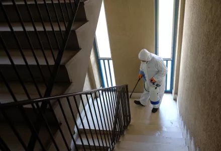 Photo of a man wearing a protective suit sanitizing the stairway of a public housing building to prevent the spreading of the coronavirus, in the neighborhood of Spinaceto, on the outskirts of Rome, Monday, March 30, 2020. 