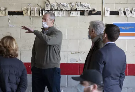 Massachusetts Gov. Charlie Baker, center, wears a protective mask while visiting the Battelle N95 decontamination site, Saturday, April 11, 2020, in Somerville, Mass.