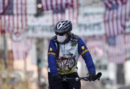 A bicyclist wears a face mask for protection against the new coronavirus while pedaling through Larimer Square early Saturday, April 25, 2020, in downtown Denver.