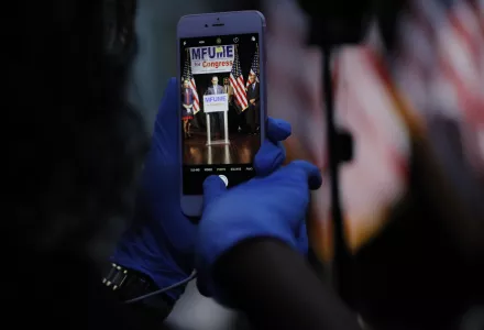 A staff member in the Kweisi Mfume campaign uses gloves while holding a cell phone during an election night news conference at his campaign headquarters after Mfume, a Democrat, won Maryland’s 7th Congressional District special election, Tuesday, April 28, 2020, in Baltimore.